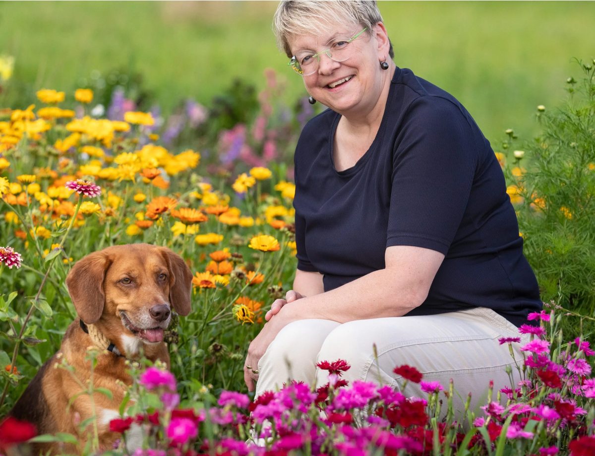 Claudia Eret, die Futterflüsterin, mit ihrem Hund im Blumenfeld